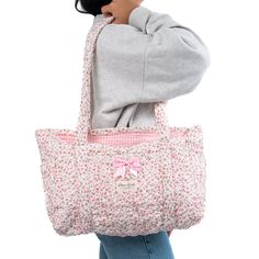 Our Peony Tote Bag is a cozy and stylish bag that combines every-day convenience with a classic design. It features 3 exterior pockets, and a bow for an added touch of elegance.   The quilted exterior boasts a beautiful floral pattern, complemented by the classy pink gingham interior.    Ideal for carrying books and groceries, or hauling beach gear and gym clothes, this bag is a must have for anyone who values versatility.  Size: 16" x 12" x 4" Gingham Interior, Saved Money, Mini Makeup Bag, Large Makeup Bag, Vanity Bag, Quilted Tote Bags, Beach Gear, Quilted Totes, Gym Clothes