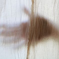 a blurry image of a person's hand through sheer curtains