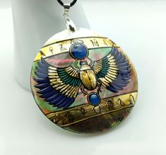 Mother of pearl sacred Egyptian Scarab necklace painted directly on mother of pearl for a 3D perspective Ancient Egypt's sacred blue and gold color (gold leaf) with hieroglyphic inscriptions Protection charm Absolutely jaw-dropping and one of a kind Entirely hand painted and hand made, signed Atlantic mother of pearl, thick shell Mother of pearl back D.6cm Jewellery cord full length approx. 60cm, adjustable Lobster claw clasp Gold Abalone Shell Pendant Jewelry, Gold Abalone Shell Necklace In Unique Style, Unique Gold Abalone Shell Necklaces, Unique Gold Abalone Shell Necklace, Unique Gold Necklace With Abalone Shell, Artisan Mother Of Pearl Jewelry Gift, Unique Gold Jewelry With Abalone Shell, Gold Bohemian Abalone Shell Necklace, Handmade Mother Of Pearl Pendant Necklace