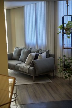 a living room filled with furniture next to a window covered in white drapes and curtains