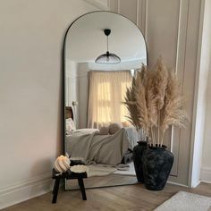 a mirror sitting on top of a wooden floor next to a vase filled with flowers