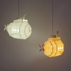 two lights that look like spaceships hanging in the air with one light turned on