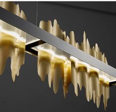 an artistic light fixture hanging from the ceiling with dripping yellow liquid on it's sides