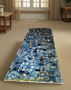 a long table covered in lots of blue and white glass pebbles next to a window