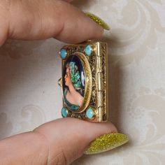 A vintage French handpainted locket; crafted in 14k yellow gold. This ornate locket is adorned with four round turquoise stones at each corner. Opens from the left side, inside of enamel picture is 'France' handwritten. This lady has a story and you were meant to be a part of hers. Previously loved, this estate locket is in excellent condition. Vintage Enamel Keepsake Jewelry, Antique Hand Painted Jewelry Gift, Antique Hand Painted Jewelry For Gifts, Antique Hand Painted Jewelry For Gift, Floating Diamond Ring, Unicorn Pendant, Estate Rings, Vintage Lockets, Turquoise Stones