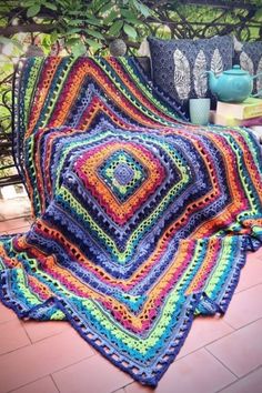 a crocheted blanket is laying on the ground next to a potted plant