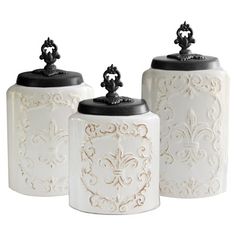 three white canisters with black lids and designs on the top, one is empty