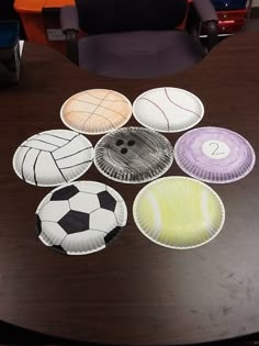 paper plates with different designs on them sitting on a wooden table in front of a chair