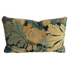 a blue and yellow floral pillow on a white background with an orange flower in the center