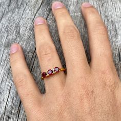 Three gorgeous little faceted garnet gemstones flanked with two tiny diamonds besides the middle one and set in gold vermeil. The open band is adjustable allowing it to be sized up a size. Dainty Gold Plated Crystal Ring For Gift, Garnet Ruby Ring As Birthstone Gift, Ruby Ring As Birthstone Gift, Dainty Red Ruby Ring As A Gift, Yellow Gold Gemstone Midi Rings As Gift, Gift Yellow Gold Gemstone Midi Rings, Yellow Gold Garnet Rings For Gifts, Adjustable Red Birthstone Ring As A Gift, Gift Yellow Gold Midi Rings With Gemstones