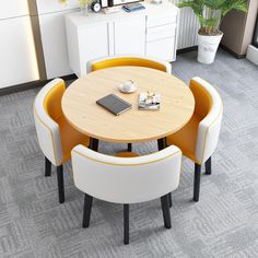 a table with four chairs around it and a laptop on the other side, in an office setting