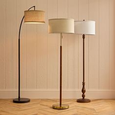 three floor lamps on wooden floors in front of a white wall and wood flooring