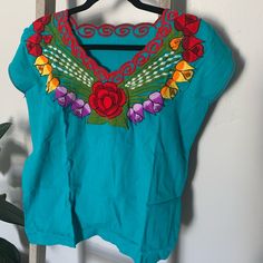 Hand-Embroidered Blouses Made In Oaxaca, Mexico. Brand New. Fits Like A Small Or Medium. Blue V-neck Top With Floral Embroidery, Blue Cotton Top With Floral Embroidery, Blue V-neck Embroidered Top With Floral Details, Blue Folk Style Top With Embroidered Hem, Casual Blue Embroidered Short Sleeve Top, Blue Folk Embroidered Top With Embroidered Neckline, Blue Folk Embroidered Top With Neckline Detail, Blue Folk Style Top With Embroidered Neckline, Blue Folk Style Embroidered Top