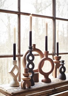 an assortment of candles sitting on top of a window sill