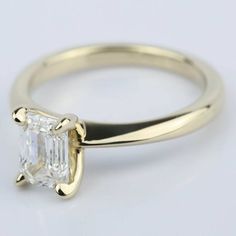 a yellow gold ring with an emerald cut diamond