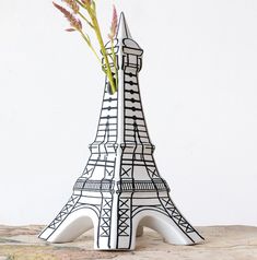 a vase with flowers in it sitting on a table next to the eiffel tower