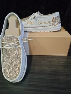 a pair of white shoes with silver sequins on them sitting next to a box