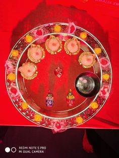 a plate that has been decorated with flowers and candles on it, sitting on a red table cloth