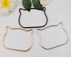 three metal cat shaped cookie cutters sitting next to each other on a white surface