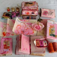 many different types of fabric and thread on a white table cloth with pink flowers in the center