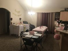 a room filled with tables and chairs next to a wall covered in pink tissue pom poms