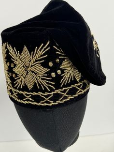 Elevate your traditional attire with our Nigerian Navy Blue & Gold Beaded Velvet Hard Hat. This exquisite headpiece is a striking blend of regal navy blue and opulent gold, adorned with intricate beadwork. Crafted for cultural celebrations and special occasions, it's a testament to elegance and tradition that will make you stand out with grace and sophistication. Artistry and Precision: Each Velvet Hard Hat is a work of art, meticulously crafted by skilled artisans who possess a deep appreciation for tradition. The attention to detail and quality construction ensure this headpiece is nothing short of perfect. Regal Color Palette: The combination of navy blue and gold is not only visually captivating but also symbolizes authority, wealth, and splendor. It adds an aura of regality to your tr Elegant Gold Costume Hats And Headpieces For Ceremonial, Traditional Gold Costume Hats For Party, Embroidered Gold Cap Hat, Gold Embroidered Cap Hat, Gold Embroidered Cap, Traditional Gold Headpieces For Celebration, Adjustable Gold Hat For Ceremonial Occasions, Traditional Gold Structured Crown Headpiece, Traditional Gold Headpiece With Structured Crown