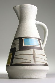 a white vase with blue and brown designs on it's side, against a gray background