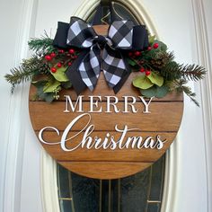 a merry christmas sign hanging from the side of a door with evergreens and pine cones