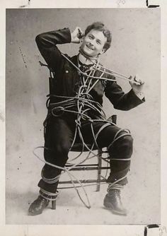 an old black and white photo of a man sitting in a chair tied up with ropes