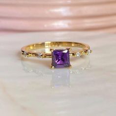 a gold ring with an amethorate and diamonds on it, sitting on a table