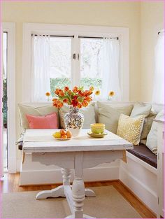 a table with flowers in a vase on top of it next to a couch and window