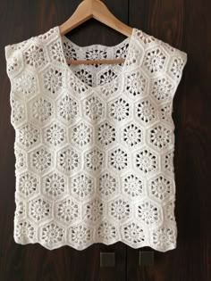 a white crocheted top hanging on a wooden hanger