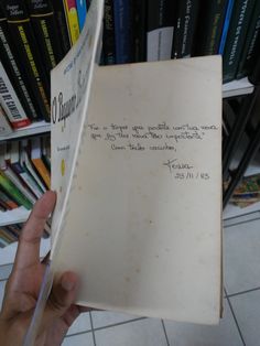 a hand holding an open book with writing on it