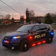 a police car is parked on the side of the road at dusk with its lights on