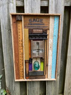 an old fashioned wooden box with different colored items in it's frame on the side of a fence