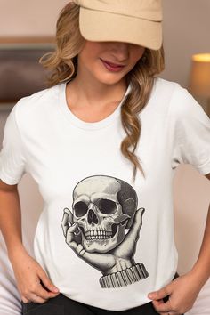 Unleash your inner gothic spirit with our Hand Holding Skull T-Shirt. This vintage-inspired tee features an intricately designed skeleton hand cradling a skull, perfect for those who appreciate dark, edgy fashion. The detailed artwork embodies the essence of gothic style, making it an ideal choice for Halloween, horror enthusiasts, or anyone who loves unique and bold designs. Made from high-quality fabric, this unisex T-shirt offers both comfort and durability. Wear it to make a statement and showcase your love for all things gothic and spooky. We utilize the authentic Bella Canvas 3001 brand, renowned for its UNISEX design, making it one of the most sought-after shirts in the market. Prior to placing an order, kindly refer to our size chart. It can be located in both the listing's images Gothic Short Sleeve T-shirt With Skull Print, Skull Print Graphic Tee For Alternative Fashion, Graphic Tee With Skull Print For Alternative Fashion, Graphic Tee Tops With Skull Print For Alternative Fashion, Gothic Cotton Top With Skull Print, White Grunge Tops With Skull Print, White Gothic T-shirt For Streetwear, Skull Print Crew Neck Top For Alternative Fashion, White Skull Shaped Grunge T-shirt