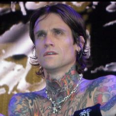 a man with tattoos and piercings on his chest holding a microphone in front of him