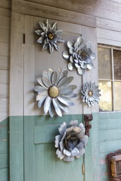 three metal flowers are mounted to the side of a door, and one is hanging on a wall