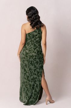 a woman in a green dress is looking back at the camera and she has her legs crossed