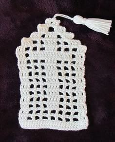 a white crocheted doily with a tassel hanging from the side on a purple background