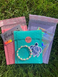 three bags with different items on them laying in the grass, one has a turtle charm