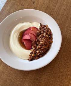 a white bowl filled with yogurt, granola and sliced fruit on top