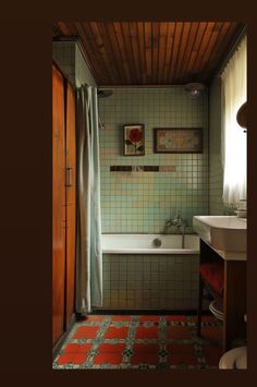 a bathroom with green and red tiles on the floor, tub, sink and toilet