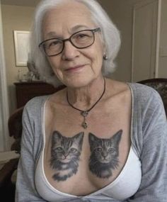 an older woman with two cats tattooed on her chest and chest, sitting in front of a couch