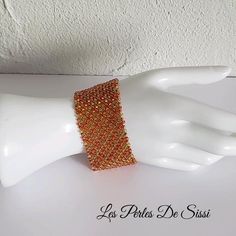 a white mannequin with an orange beaded bracelet on it's arm