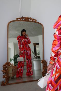 a woman standing in front of a mirror wearing red and pink pajamas with matching heels