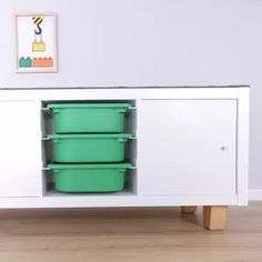 a white sideboard with three green plastic containers on the bottom and two wooden legs