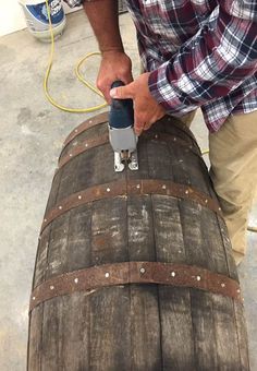 a man is using a drill to fix a wooden barrel