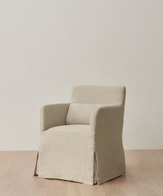 a beige chair sitting on top of a wooden floor next to a white wall in an empty room