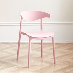 a pink chair sitting on top of a hard wood floor next to a white wall